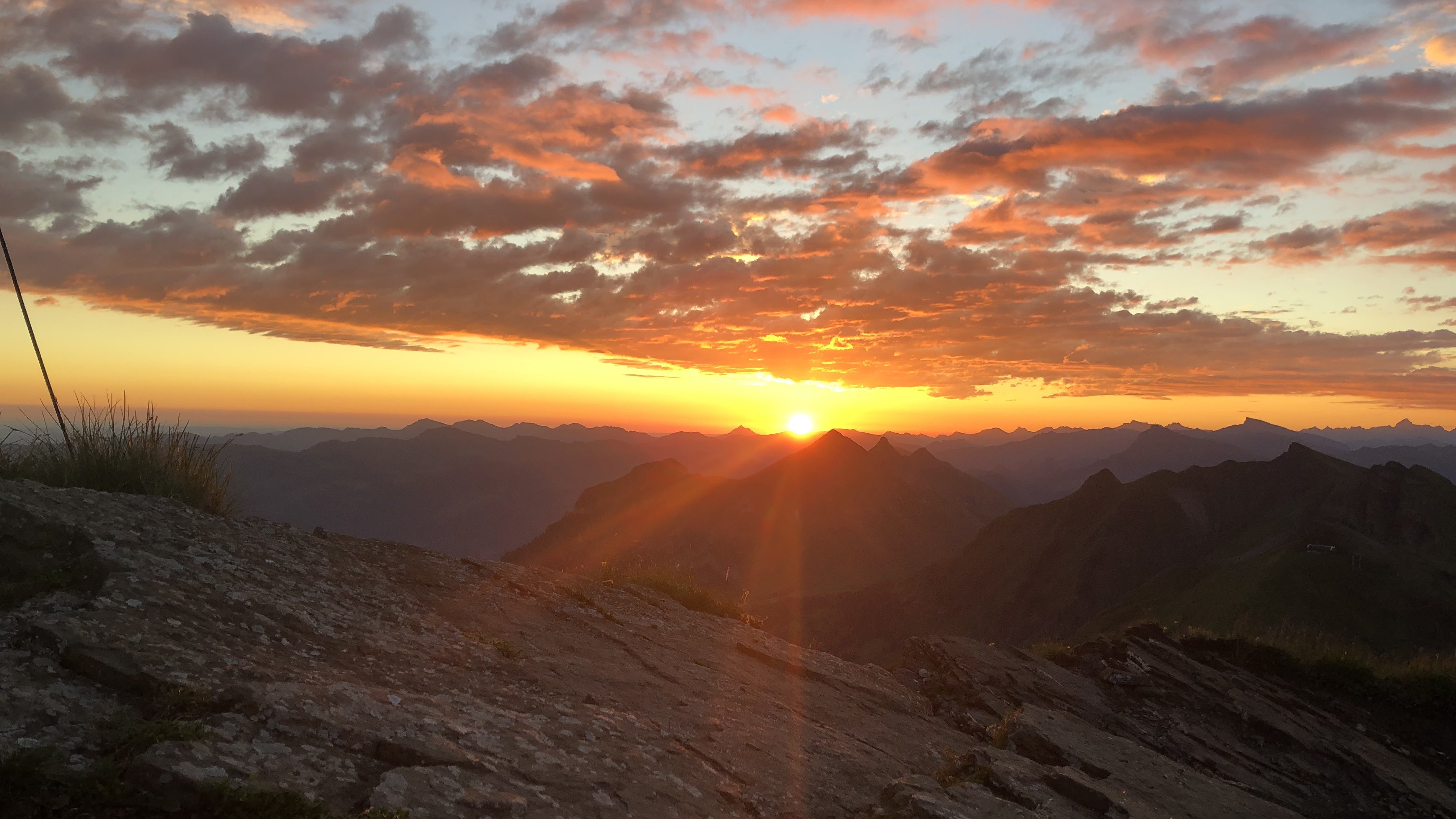 Sonnenuntergang über einer majestätischen Berglandschaft mit leuchtenden Wolken.