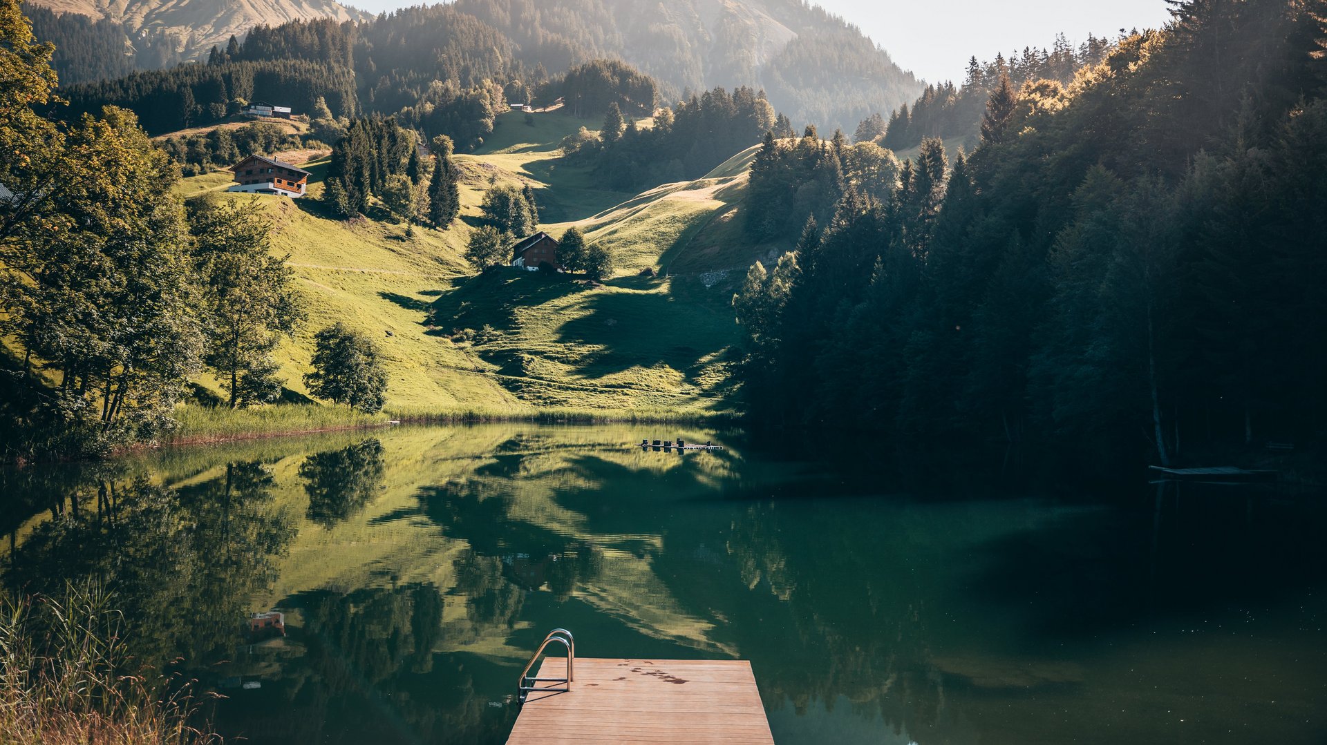 Beruhigende Berglandschaft mit einem See, umgeben von Hügeln und Bäumen, ideal für Naturfreunde.