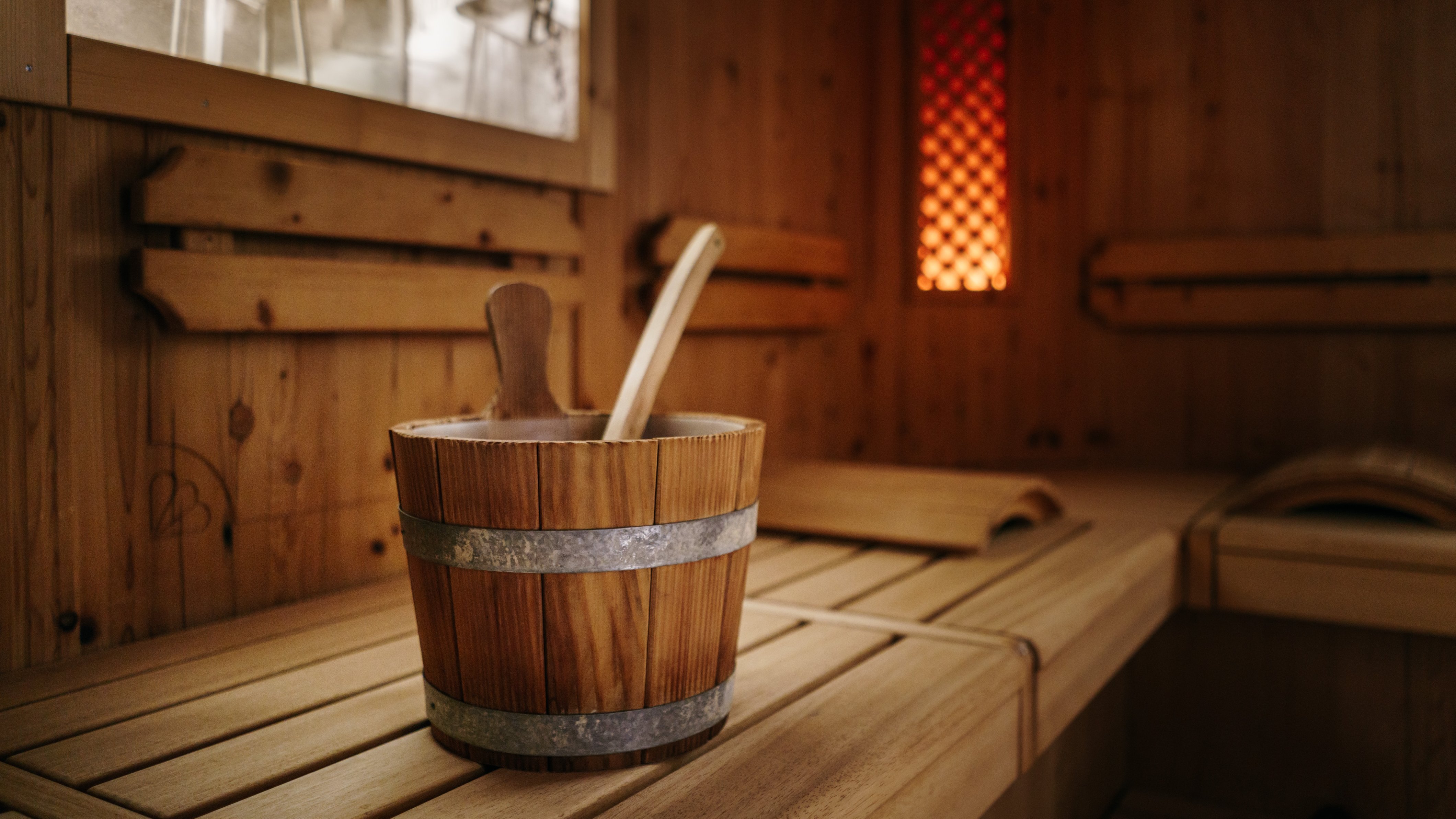 Innenansicht einer Holzsauna mit einem Eimer und einem Schöpflöffel zur Entspannung