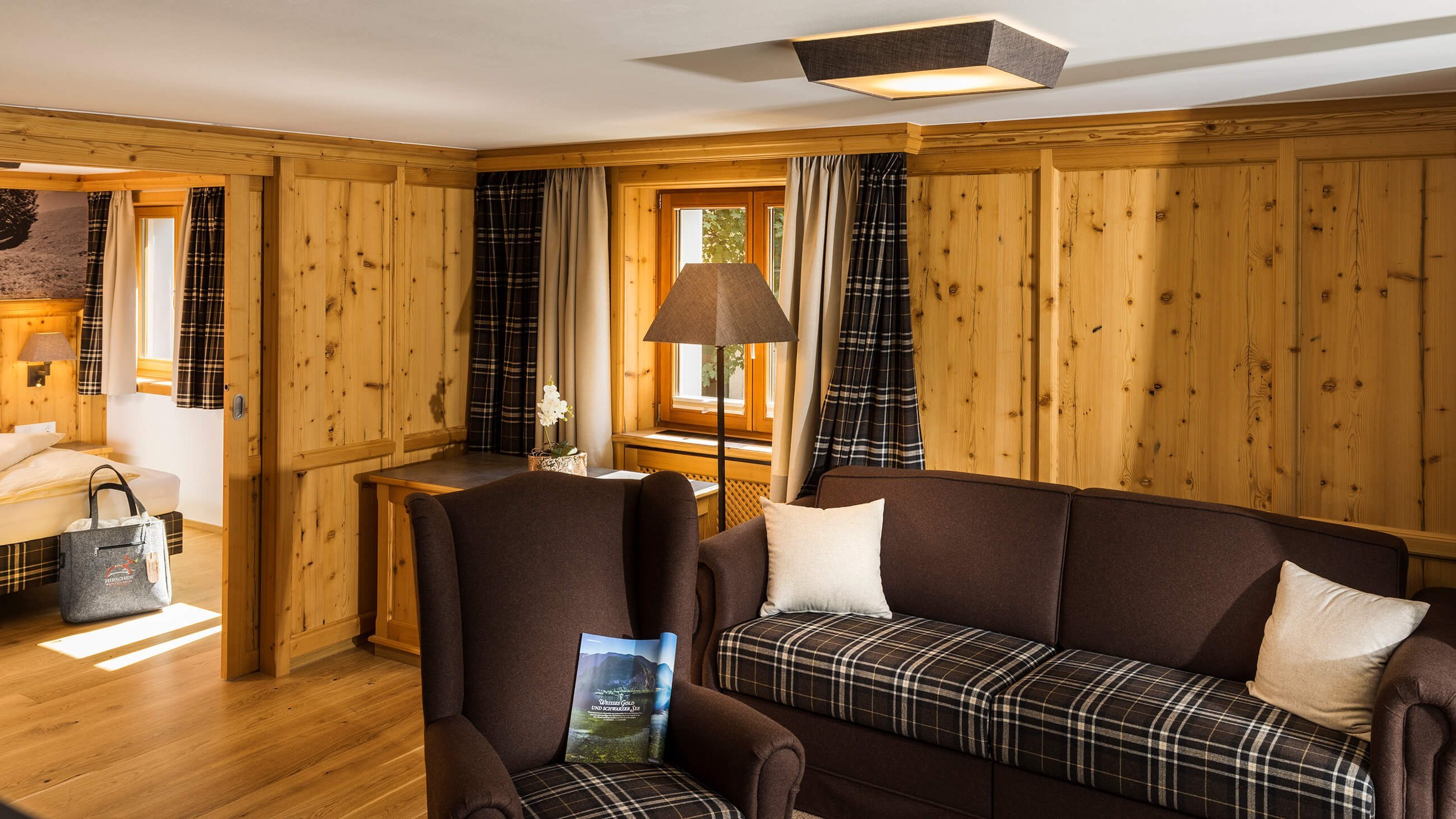 Cozy Luxury Suite at Hirschen Wohlfühlhotel A wooden interior hotel room featuring a seating area with a sofa and armchairs.
