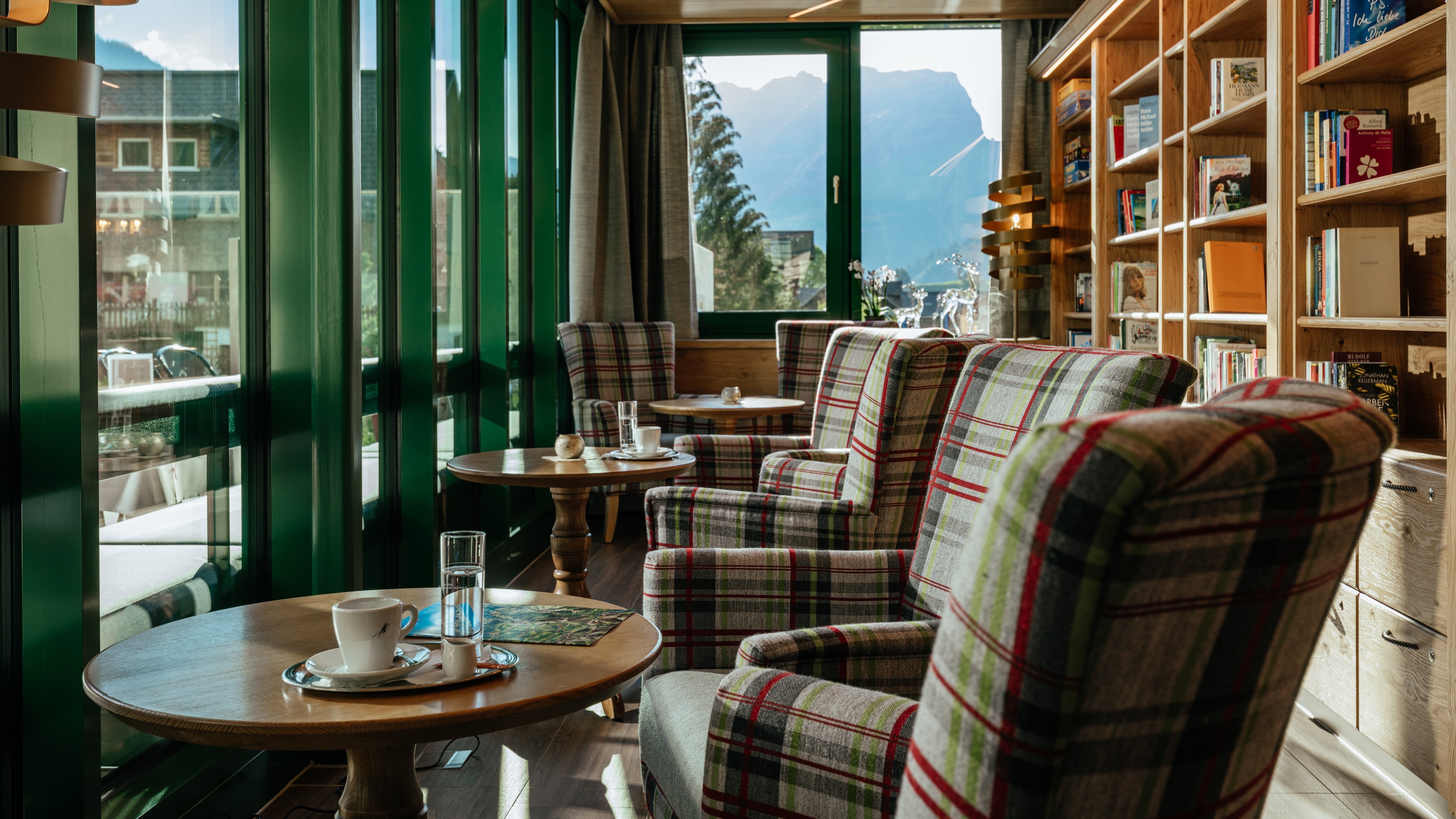 Cozy hotel lounge with plaid armchairs and wooden tables overlooking mountains for relaxation