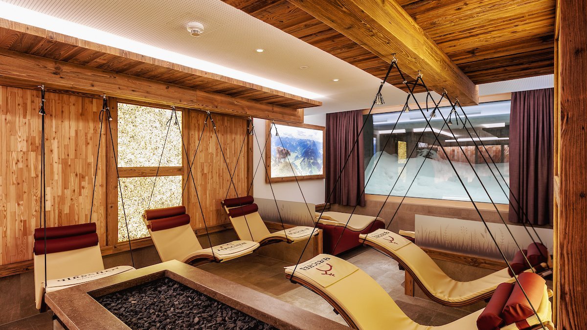 Loungebereich mit hängenden Liegen und Steinakzent im Spa-Bereich des Hotels. Karftort für Ruhe und Erholung.